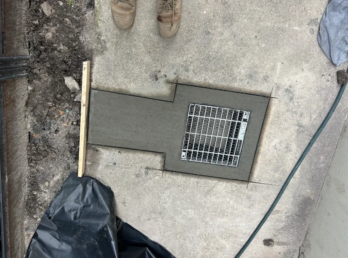 Metal drainage grate set into a newly worked concrete surround