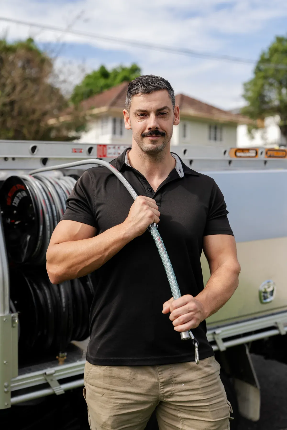 Plumber holding jetting equipment beside a work ute