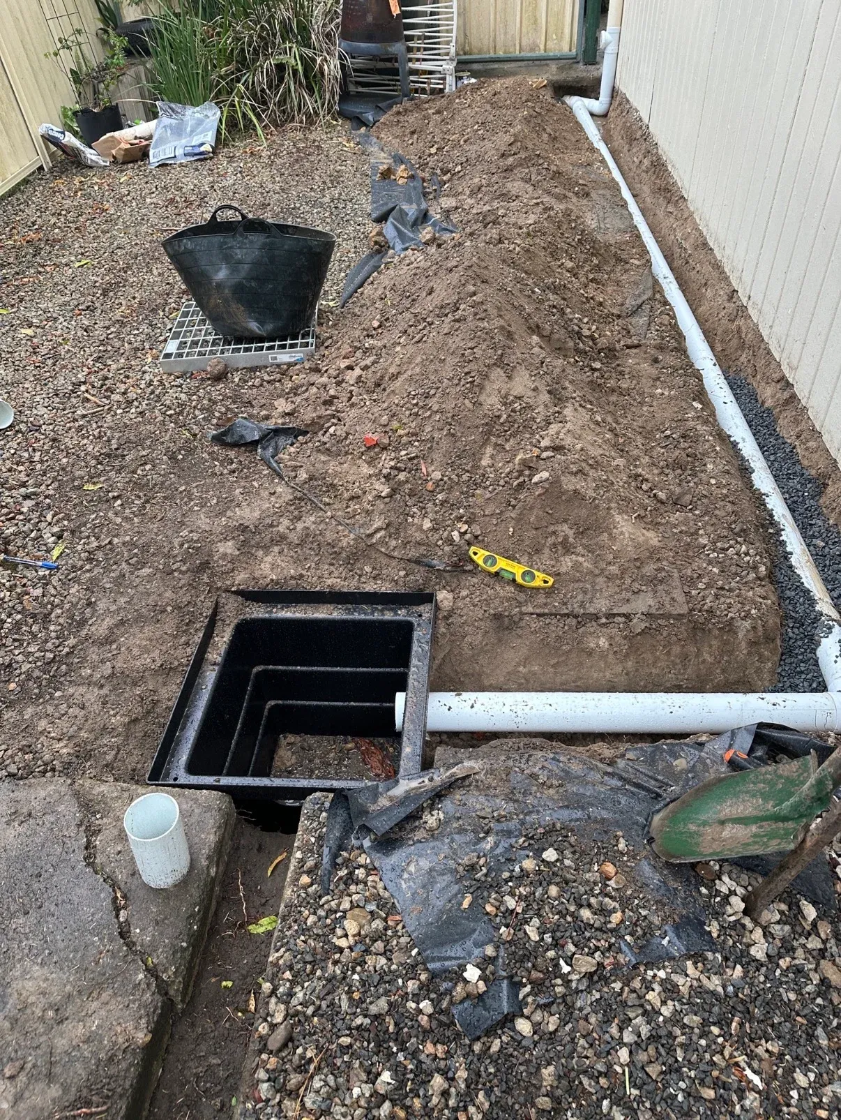 Stormwater pipework and drainage pit beside a building