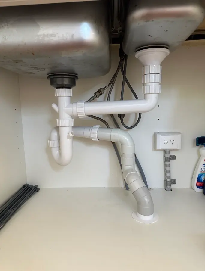Waste trap and connecting pipework beneath a double kitchen sink