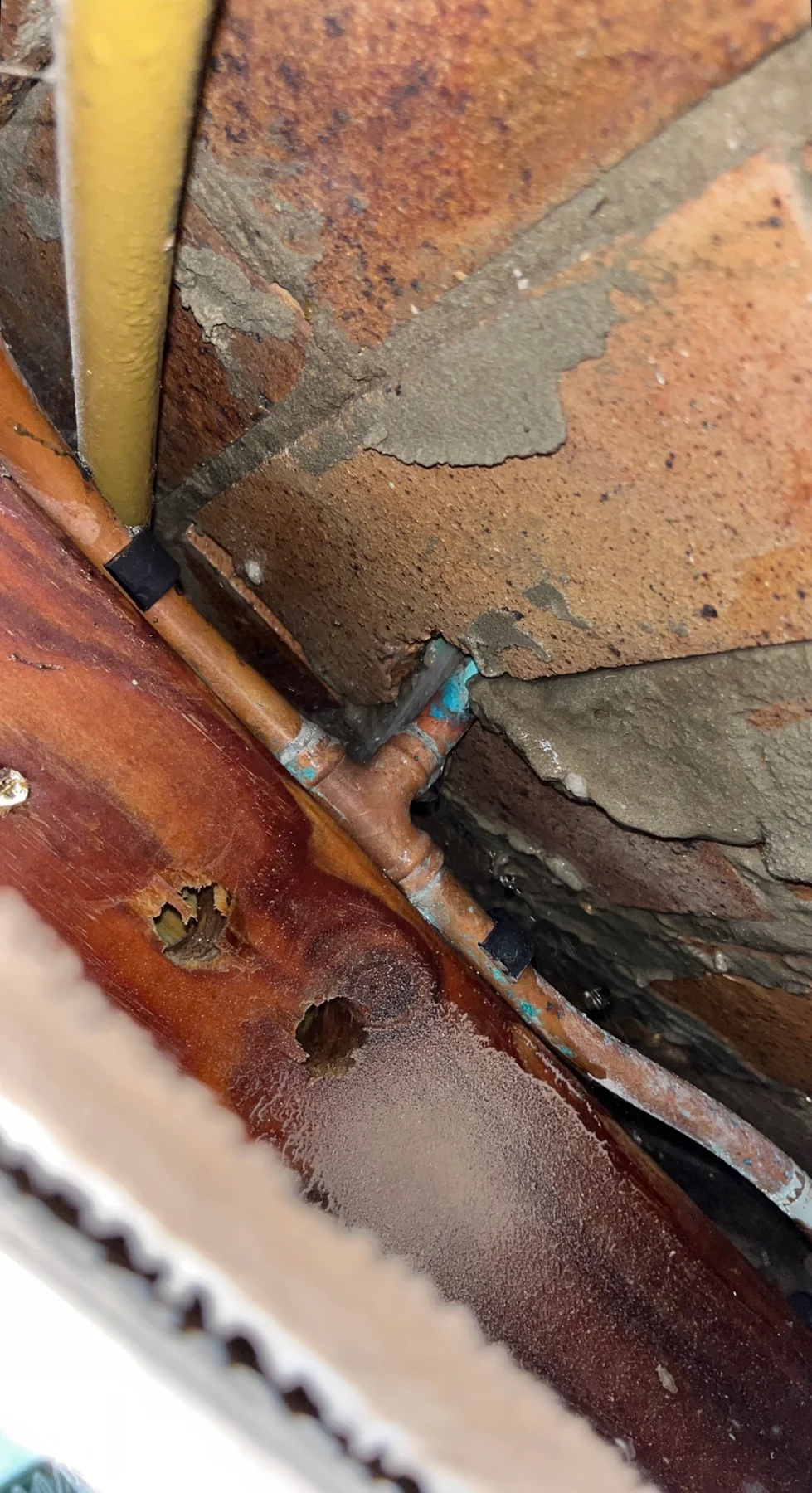 Water leaking from copper pipework exposed in a brick wall cavity