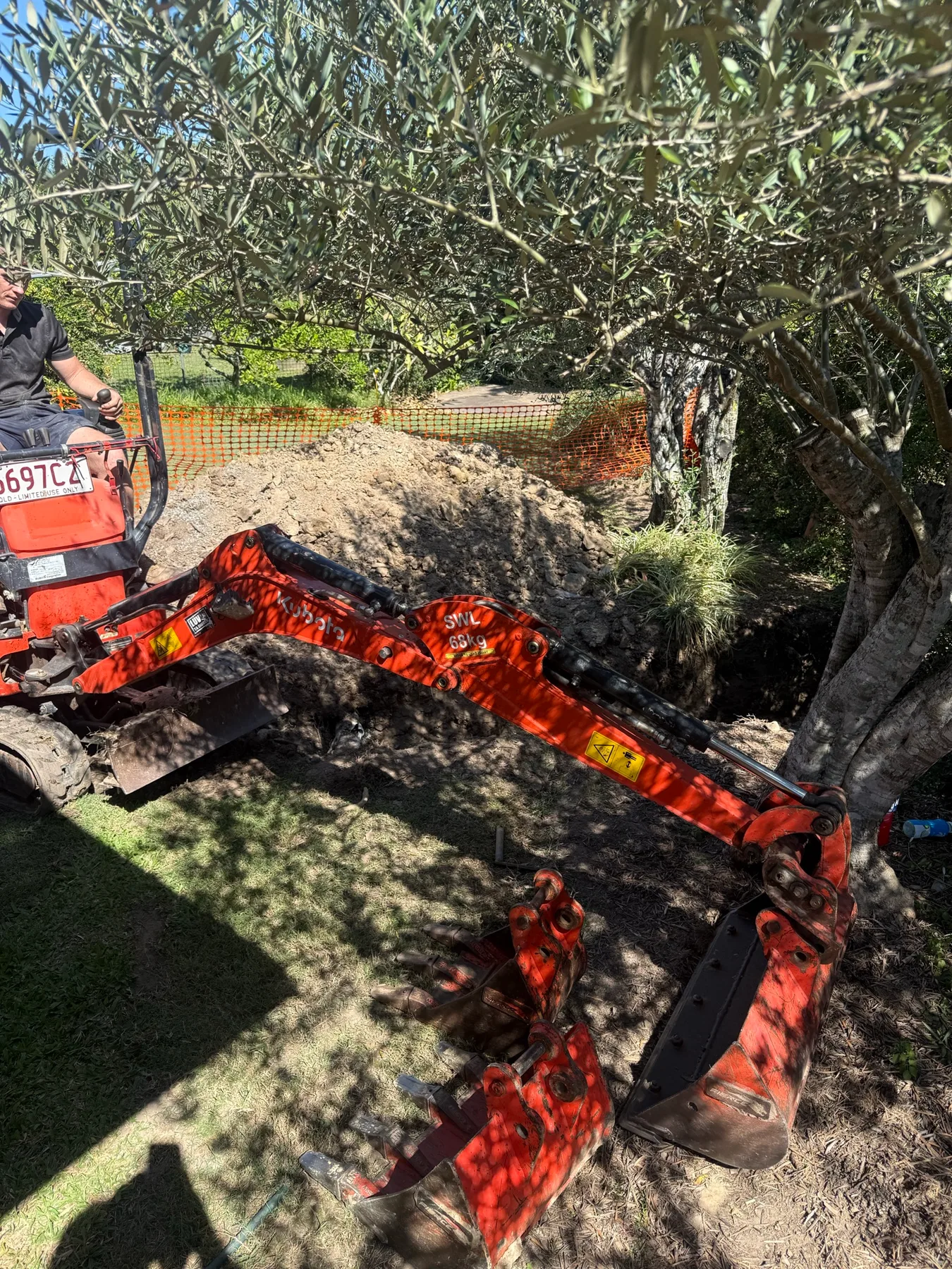 Mini-excavator beside exposed drainage pipework